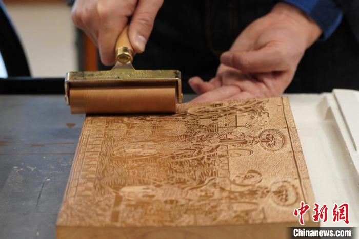 圖為徐晉林工作室工作人員正在給雕好壁畫的版面滾油墨?！【琶赖┰?　攝