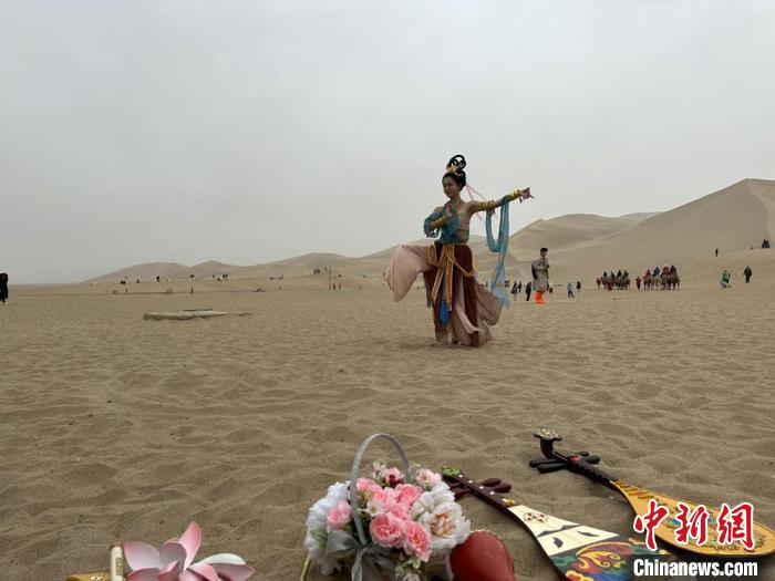 圖為2023年4月底，敦煌大漠“逐舞者”奧楠在鳴沙山月牙泉景區(qū)視頻直播敦煌舞?！●T志軍 攝