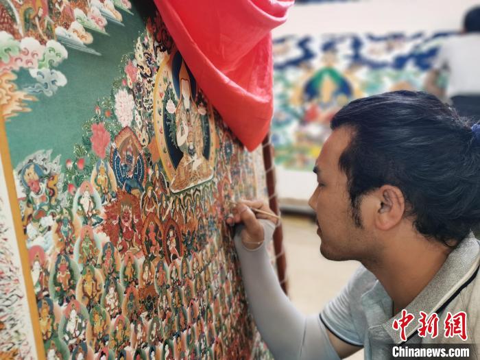 圖為更登才讓的徒弟繪畫唐卡?！?zhí)砀?攝