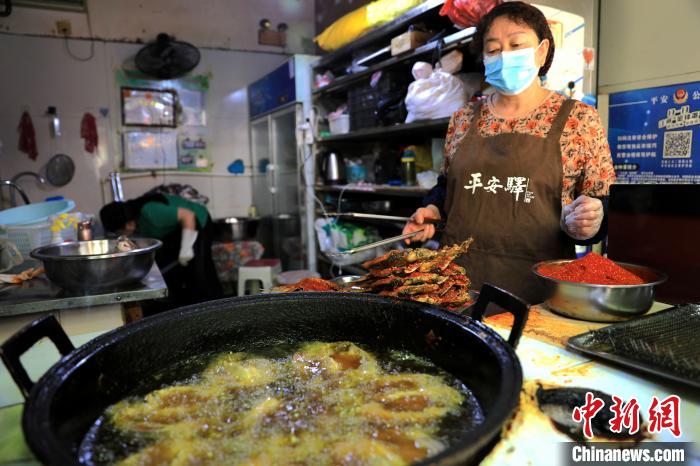 圖為平安驛·河湟民俗文化體驗地內(nèi)的商戶炸干板魚?！⊙Φ?攝
